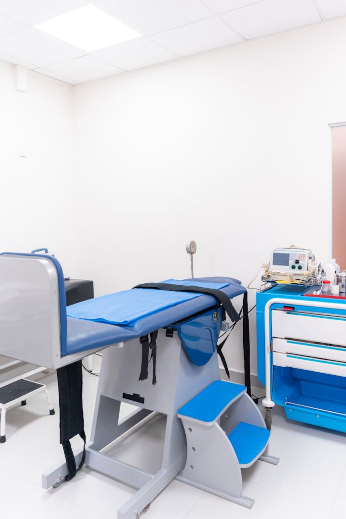 Clean and well-equipped hospital examination room with blue medical equipment and diagnostic devices.